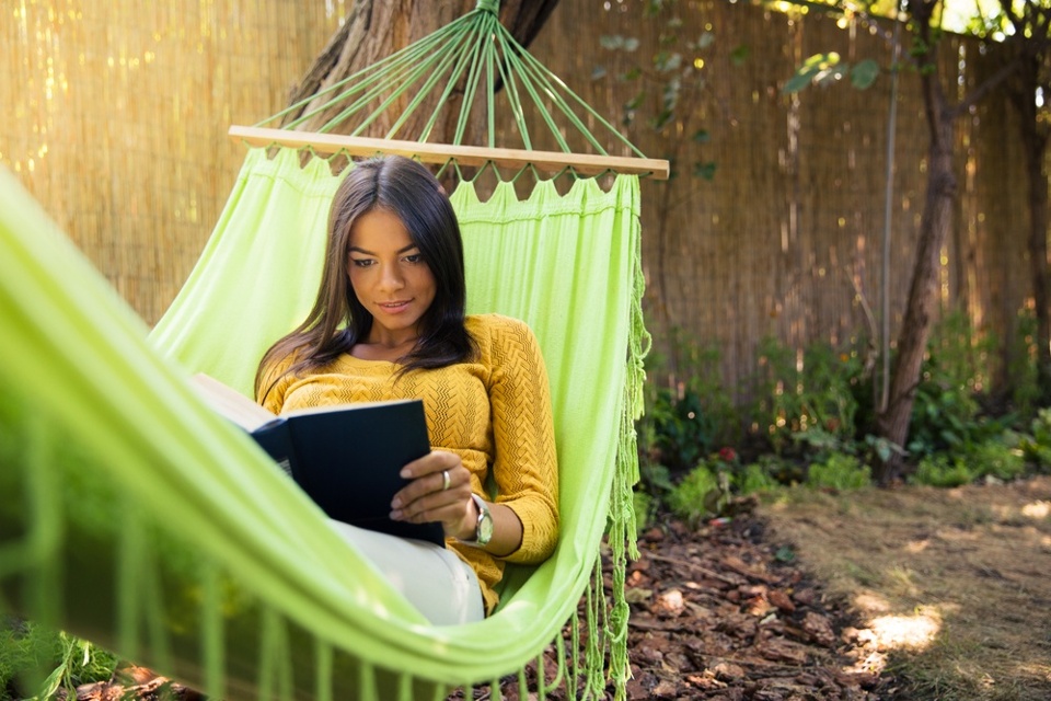 Image of a woman reading in a hammock while her answering service handles her calls